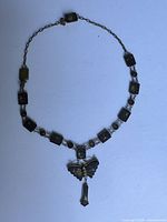 Full view of the necklace showing rectangular links with gold inlay and central butterfly pendant with dangling charm.