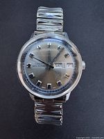 Front view of the vintage Timex Marlin watch showing silver dial with rectangular hour markers, day and date windows, and expandable metal band.