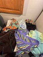 Six assorted swimsuits laid out on a surface showing a mix of bikini bottoms and one-piece suits in various colors and patterns
