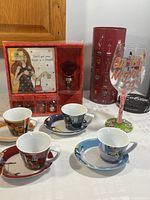 Set showing four espresso cups and saucers in front of boxed wine accessory gift set and Girls Night In wine glass
