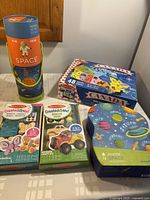Lot contents showing all puzzles and craft kits on table with packaging visible