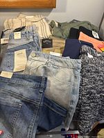 Lot of various new shorts and golf bottoms with tags laid out, showing multiple colors and fabrics