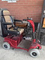 Right side view of red mobility scooter showing seat, handlebars, battery compartment and wheel condition