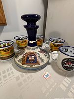 Top and side view of the Pusser's Navy Rum ceramic decanter with detailed naval-themed decorations and stopper with emblem.