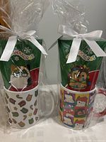 Two Squishmallow Mug and Cocoa Gift Sets wrapped in clear cellophane tied with white ribbons. Each set includes a mug and a packet of Original Squishmallows hot cocoa.