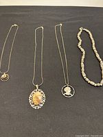Four necklaces laid out on a black surface showing length and detail of pendants.