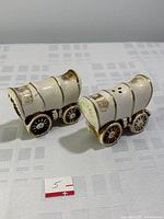 Pair of vintage covered wagon shaped salt and pepper shakers shown from angle highlighting the front and side details including tiny holes on top for dispensing.