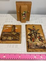 Photo showing solid wood towel or memo holder with hand-painted floral bird design and two M. Nadeau hand-carved wood plaques of a lighthouse and windmill