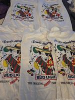 Five vintage Spuds Mackenzie Bud Light t-shirts laid out, showing front graphic design, some yellow staining visible on one shirt.