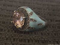 Front view showing the round faceted purple stone surrounded by marcasite details and the light blue enamel on the sides of the band.