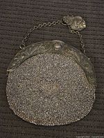 Full view of antique silver mesh purse with detailed embossed metal frame and chain handle.