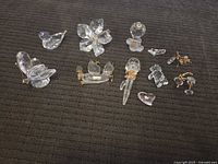 Photo of the full collection of Swarovski crystal figurines placed on black fabric, showing the variety of clear and gold-tone crystal pieces in different shapes and sizes
