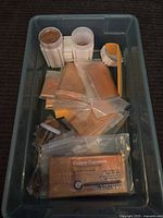Shelf box with multiple sealed rectangular copper bars, copper penny rolls in white plastic holders, and a clear plastic pack labeled 'Copper Capowns'.
