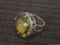 Side view of the large sterling silver ring showing engraved designs and the oval faceted yellow stone.