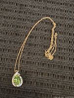 Full view of the 10k gold necklace with pendent on black textured surface