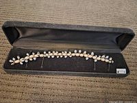 Full view of the necklace inside a black velvet-lined case showing the alternating bead pattern and sterling clasp.
