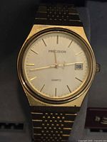 Close-up photo of the gold-tone dial of the Gruen Precision quartz watch showing the face, hands, date window, and bezel.