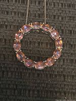 Close-up of the circular pendant showing pink oval gemstones set in sterling silver.