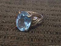 Front and angled side view showing the bright blue faceted stone and sterling markings on band.