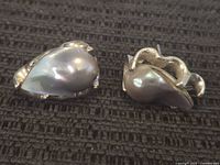 Two sterling silver earrings with large pearlescent teardrop stones on a textured dark surface.