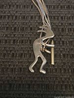 Close-up photo showing the sterling silver Kokopelli pendant with detailed flute and attached snake chain necklace.