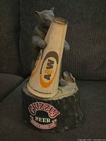 The full display featuring the grizzly bear figure clutching a cone instead of the missing bottle on a wood-like base with a Grizzly Beer sign.