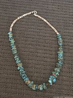 Full view of the vintage turquoise heishi necklace laid flat showing the alternating turquoise and cream-colored beads.