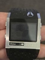 Photo of the front of the Nixon digital watch showing the rectangular stainless steel case, digital screen, and Nixon logo.