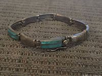 Photo of entire bracelet laid flat on fabric surface showing turquoise and plain sterling segments and clasp.