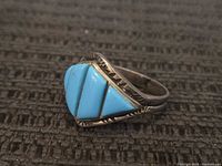 Close-up image of the vintage sterling silver ring with three turquoise stones inlaid in a geometric triangular pattern.