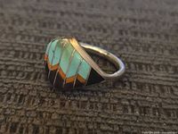 Side angle view of vintage sterling silver ring showing turquoise, coral, onyx inlay detail
