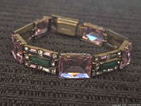 Close-up image of the vintage rhinestone bracelet showing rectangular pink rhinestones and green and clear accent stones set in gold-tone metal.