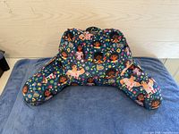 Front view of child-sized lounge chair pillow with Disney Encanto character pattern on dark blue fabric, showing armrests and supportive back.
