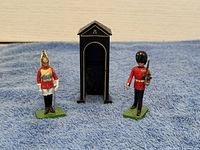 Front and back view of two British guard miniatures and black guard booth on blue cloth background