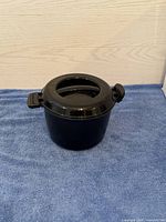 Front and side view of the black Pampered Chef microwave rice or pasta cooker showing the handles and vented lid.