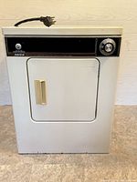 Front angled view of small Admiral clothes dryer showing black control panel with timer knob, beige door handle, white metal body, and attached power cord.