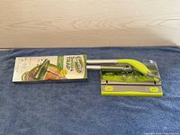 Swiffer Sweep and Trap floor sweeper with original box and handle fully set out on a blue cloth.