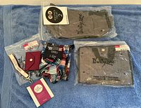 Photo showing the full lot arranged on a blue towel including socks, card holder, scrunchie, lanyard, and two packaged apparel items.