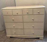 Front view of the vintage white dresser showing 10 drawers and missing handle on top left drawer.