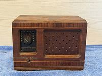 Front view of vintage Crosley tube radio showing tuning dial on left and perforated speaker grille on right with wood cabinet.