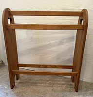 Full front view of wooden quilt stand showing two horizontal quilt bars and heart-shaped cutouts on side panels.