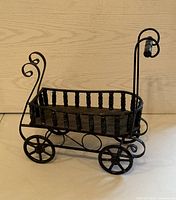 Front and side view of the black wrought iron wagon shaped planter showing the spindles and wheels in detail