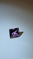 Close-up photo of a 3.81 carat natural purple amethyst gemstone, fancy square cut, showing its color and clarity.