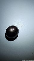 Oval black star sapphire cabochon showing the natural star pattern under lighting, highlighting the double sided star flash.