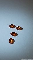 Four natural imperial sapphires in intense orange color, arranged together under lighting highlighting their clarity and faceting.
