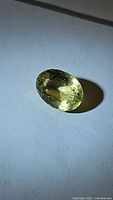 Oval cut natural lemon citrine gemstone on a white background showing clarity and color under light.