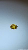 Close-up photo of an oval bright yellow sapphire gemstone on a plain background showing color and cut details