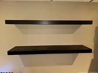 Two black floating shelves mounted on wall to show scale and color.