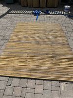 Single bamboo panel laid flat on stone patio, poles bound with wire