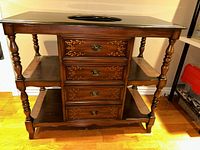 Front view of vanity showing four front drawers with carved floral designs and black sink top.